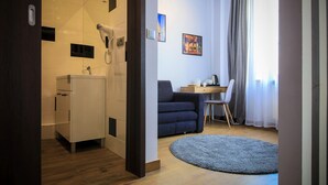 A modern room with a kitchenette, a sofa, a desk, and a large window with curtains. - Boogie Aparthouse Old Town (Wroclaw)