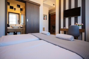 A hotel room with a large bed, a flat-screen TV, a wooden desk, and a fireplace. - Boogie Aparthouse Old Town (Wroclaw)