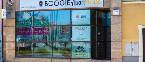 Un edificio con un letrero que indica BOOGIE Apart House, que cuenta con un gran ventanal con varios anuncios, incluyendo uno para Social WiFi.