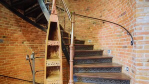 A spiral staircase with wooden steps and metal railings in a brick-walled room. - Boogie Aparthouse Old Town (Wroclaw)