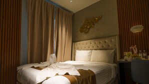 Quarto de hotel com uma cama grande, uma mesa de cabeceira com abajur e vista para o exterior pela janela.
