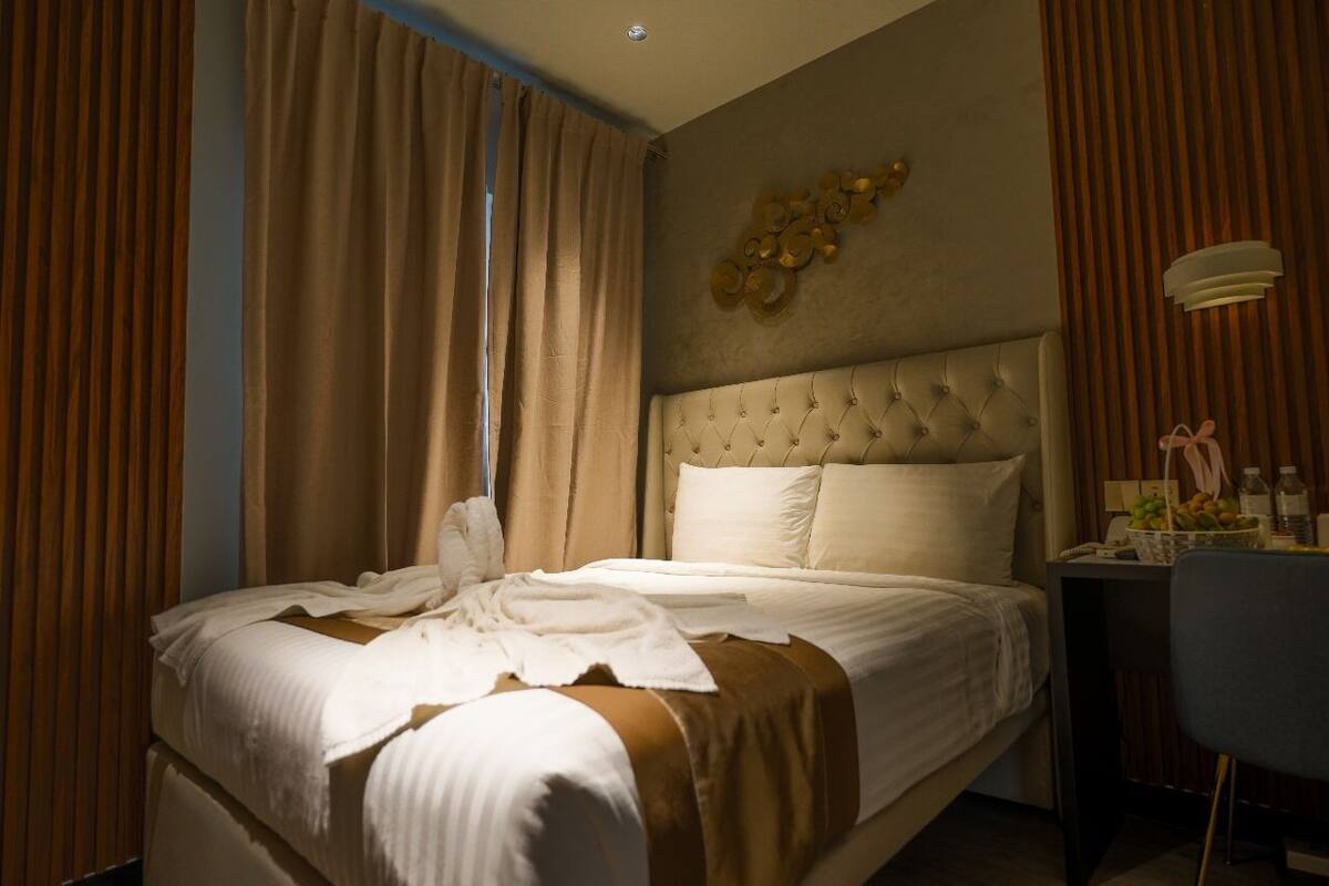 Een hotelkamer met een groot bed, een nachtkastje met een lamp, en uitzicht door het raam.