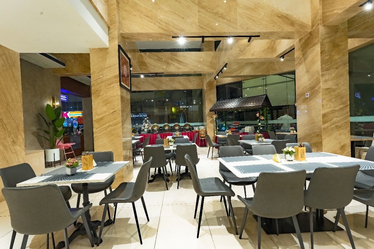 Un restaurant moderne aux murs et au plafond en marbre, doté de nombreuses tables et chaises.