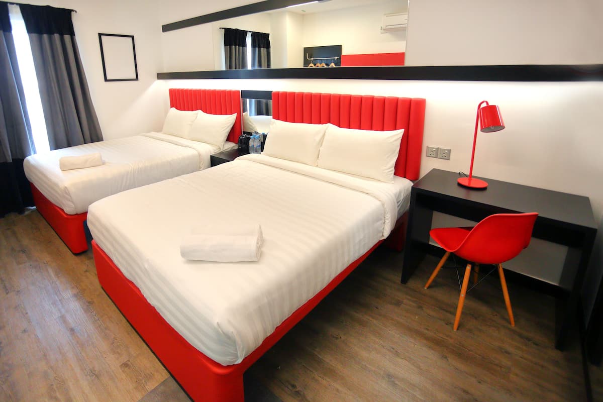 Een hotelkamer met twee bedden, een bureau, een stoel en een spiegel.