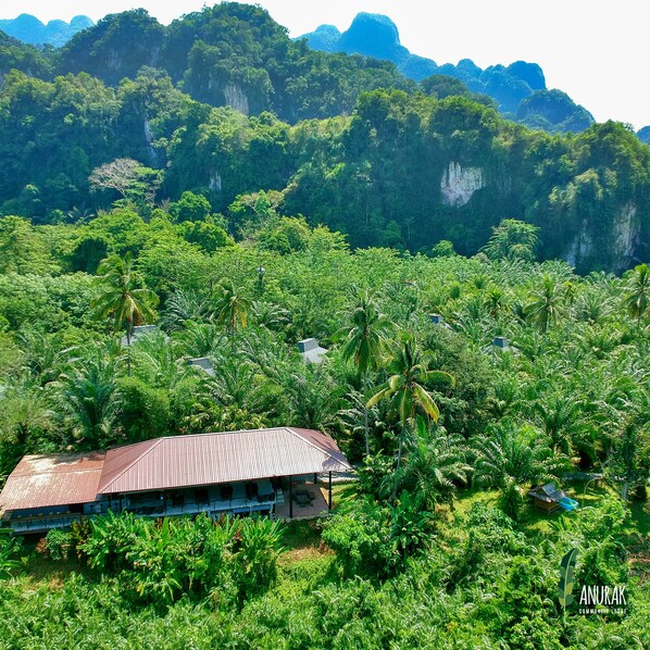 A community lodge surrounded by lush greenery and mountains.