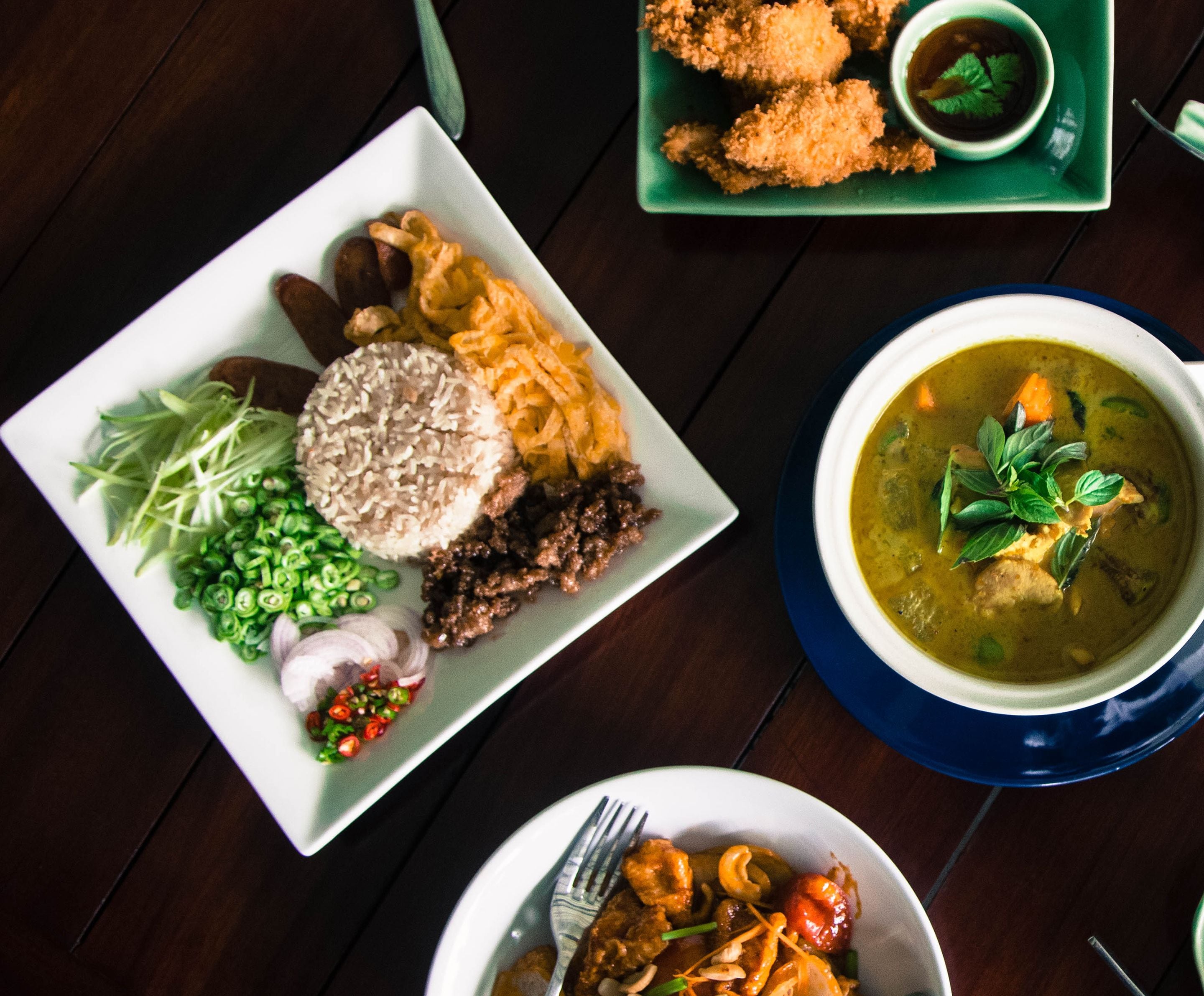 A table with a variety of dishes including rice, vegetables, and a bowl of soup.