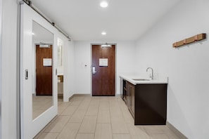Una cocina moderna con un lavamanos empotrado y armarios, una puerta de madera y un pasillo que conduce a otra habitación.