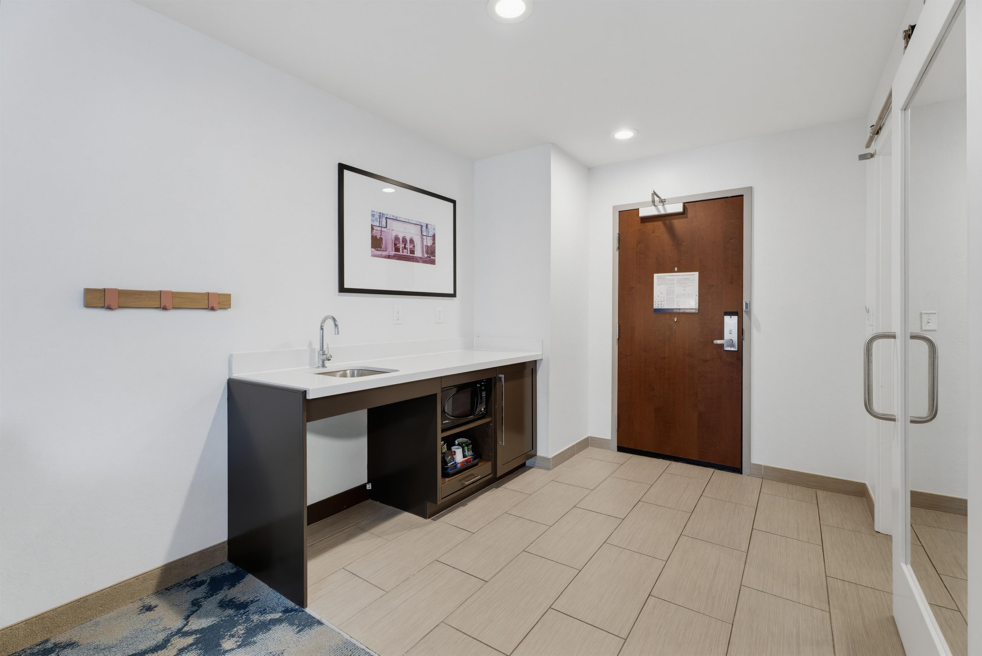Un baño moderno con lavamanos, espejo y un cuadro enmarcado en la pared.