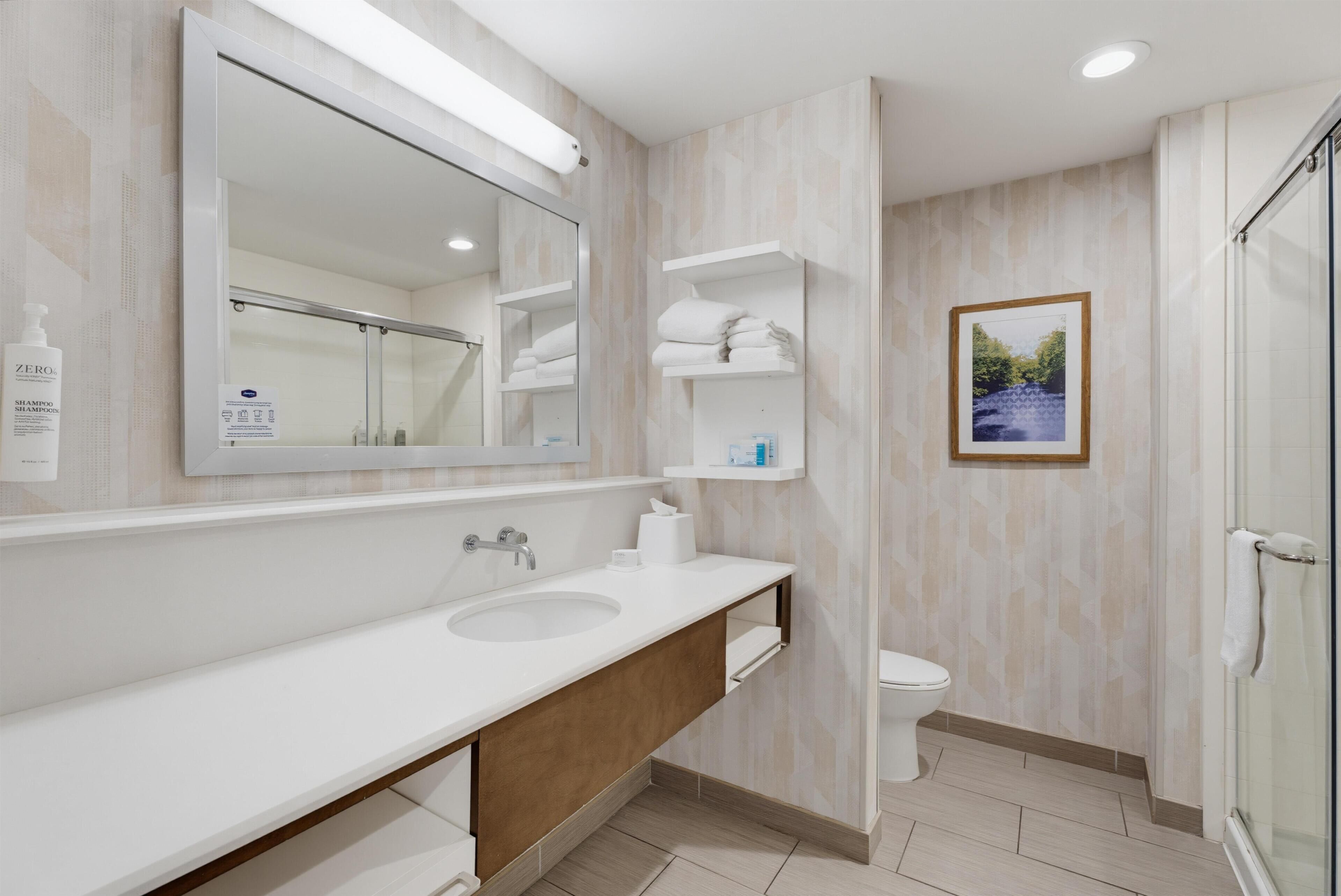Un bagno moderno con uno specchio grande, due lavabi, un water e una doccia.