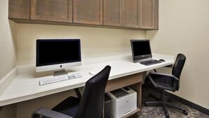 A workspace with two desktop computers, a keyboard, a mouse, and two office chairs.