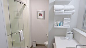 A modern bathroom with a glass-enclosed shower, a white sink, and a toilet.