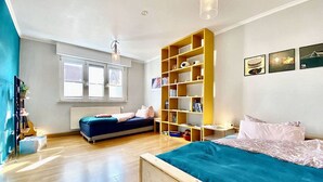 A bedroom with a bed, a sofa, a bookshelf, and a window. - Apartment Avanzato (Erfurt)