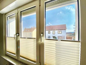 A window with a view of a residential area, a door with a handle, and a window blind. - Apartment Avanzato (Erfurt)