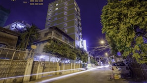 A multi-story building with balconies, a gated entrance, and a parked car. - The Mou Hotel (Phnom Penh)
