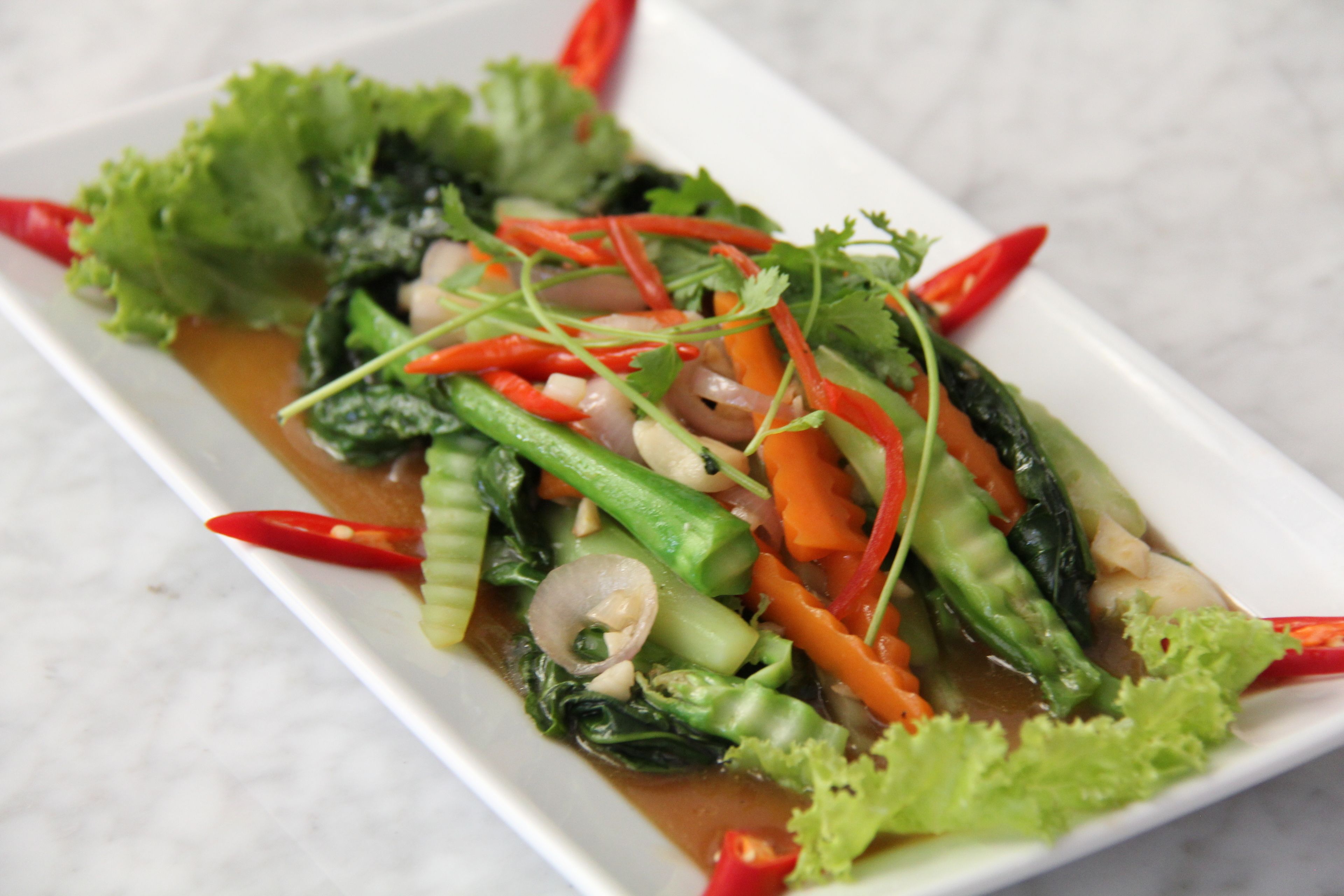 Un plat de légumes sautés, agrémentés de piments rouges et de légumes verts.