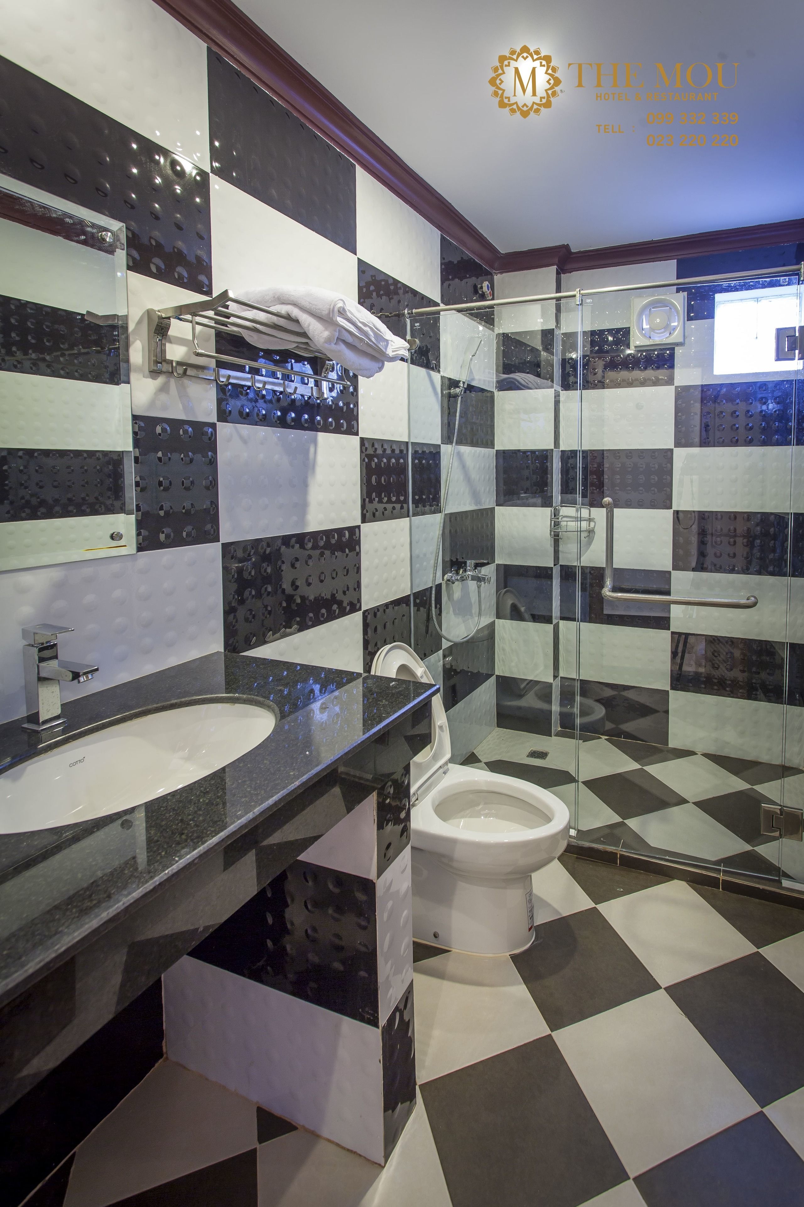 A modern bathroom with a checkered floor, a glass shower enclosure, a sink, and a toilet.