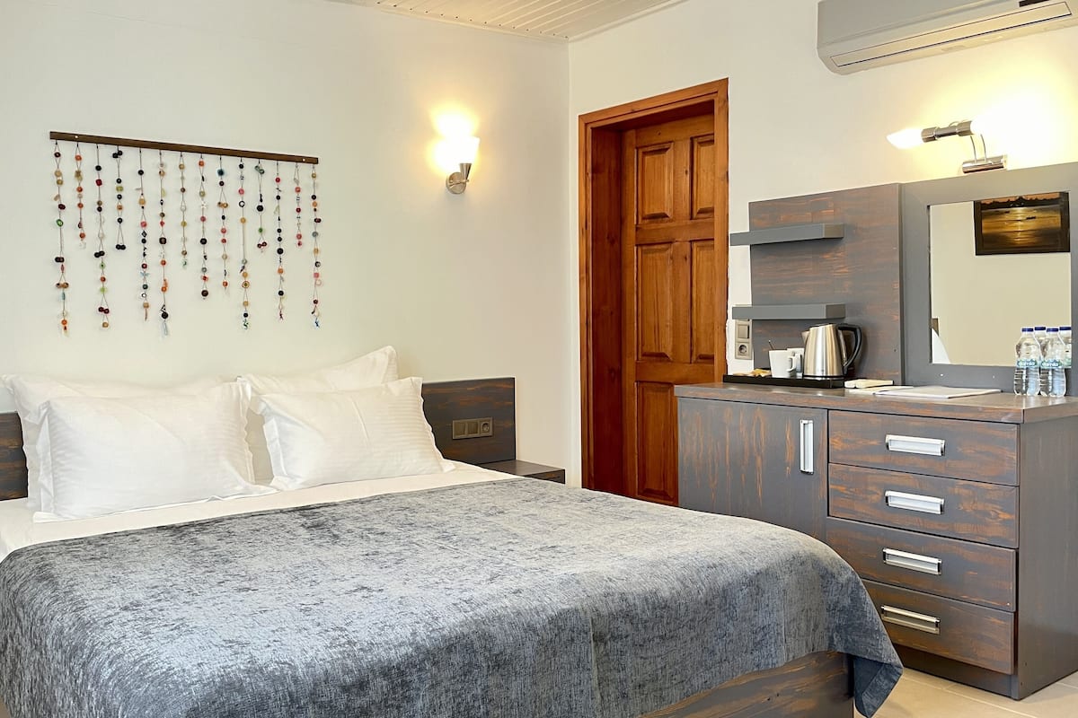 Une chambre à coucher comprenant un lit, des tables de chevet, une commode, un miroir et un luminaire fixé au mur.