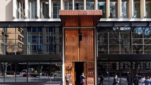 Un edificio moderno con una fachada de ventanas enrejadas y una entrada de madera.