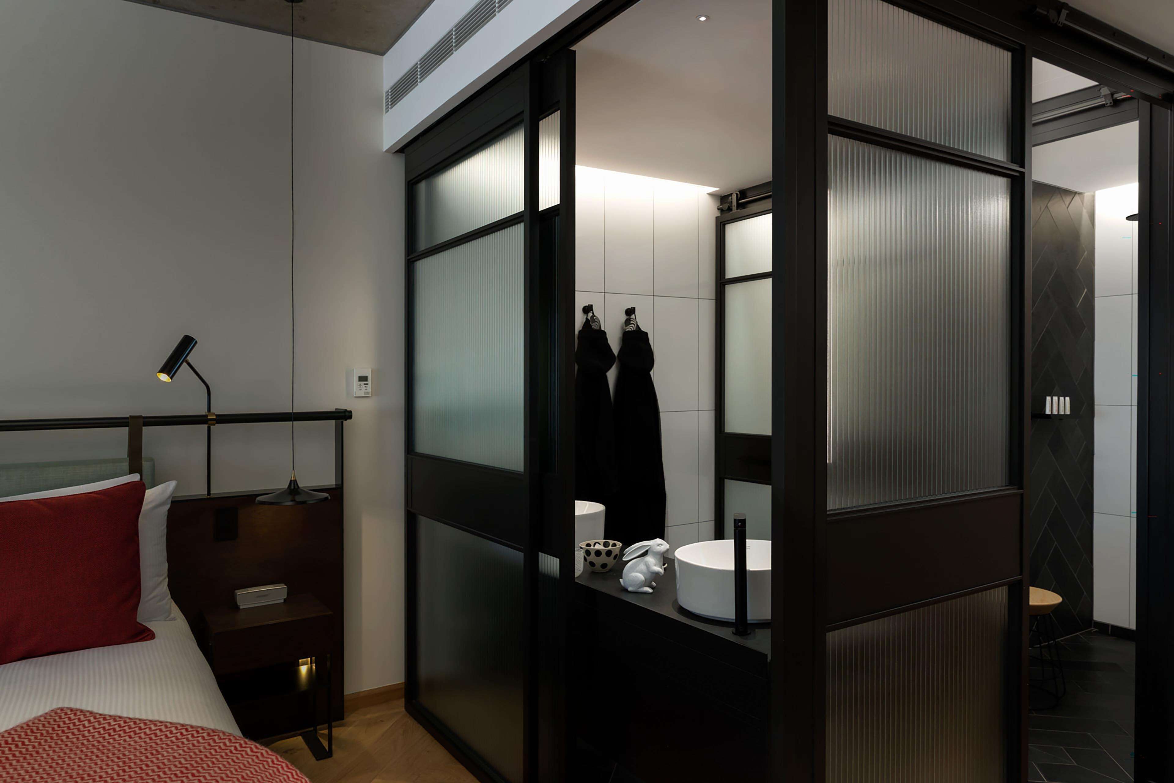 A modern hotel room with a bed, bedside table, and a large mirror.