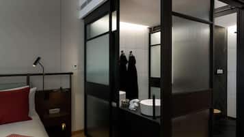 Una habitación de hotel moderna con cama, mesita de noche y un espejo grande.