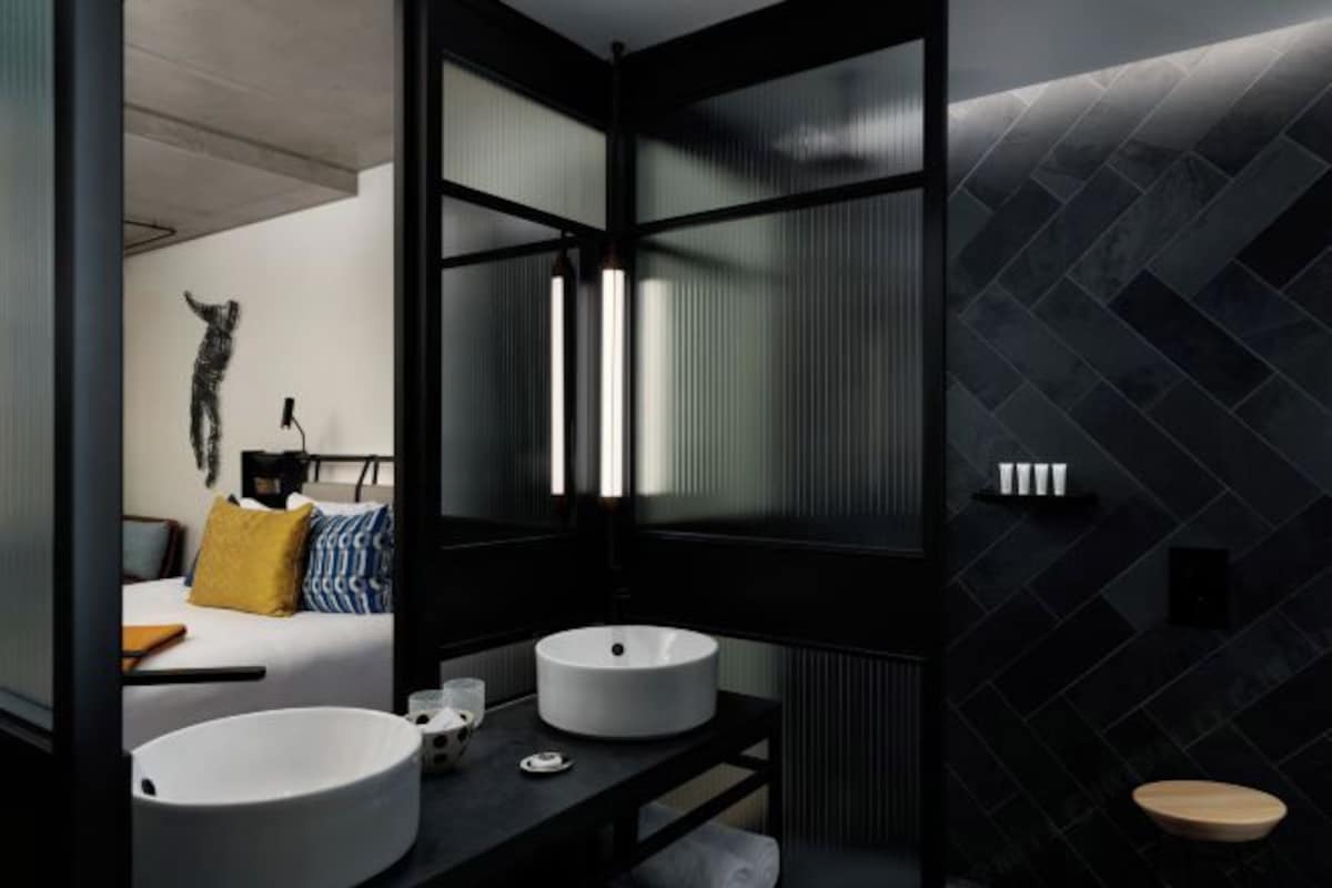 Un baño moderno con dos lavamanos redondos, un taburete de madera y una decoración de pared.