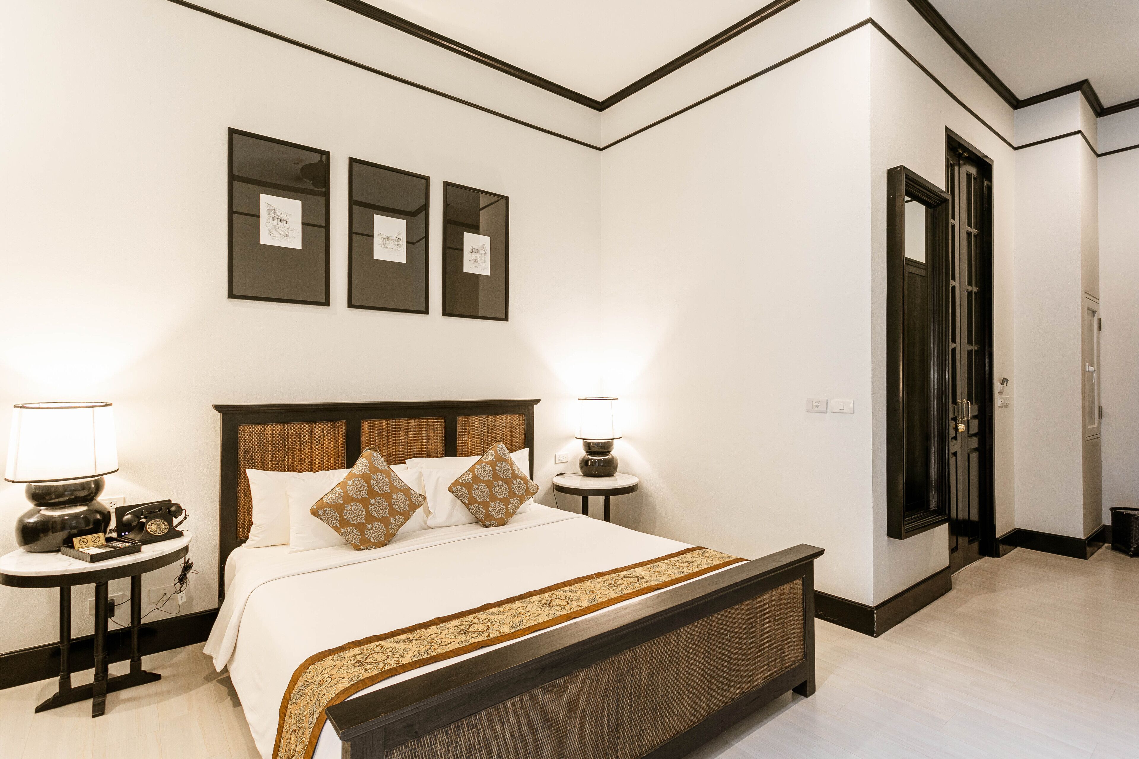 A neatly arranged hotel room with a large bed, bedside lamps, a small table, and framed artwork on the wall.