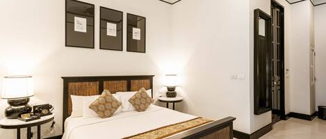A neatly arranged hotel room with a large bed, bedside lamps, a small table, and framed artwork on the wall.