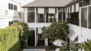Un bâtiment à deux étages doté d’une piscine, d’un espace extérieur aménagé et d’une végétation luxuriante.