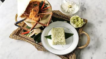 A plate of rice with a decorative leaf, a glass of water, and a decorative bowl with a seafood dish.