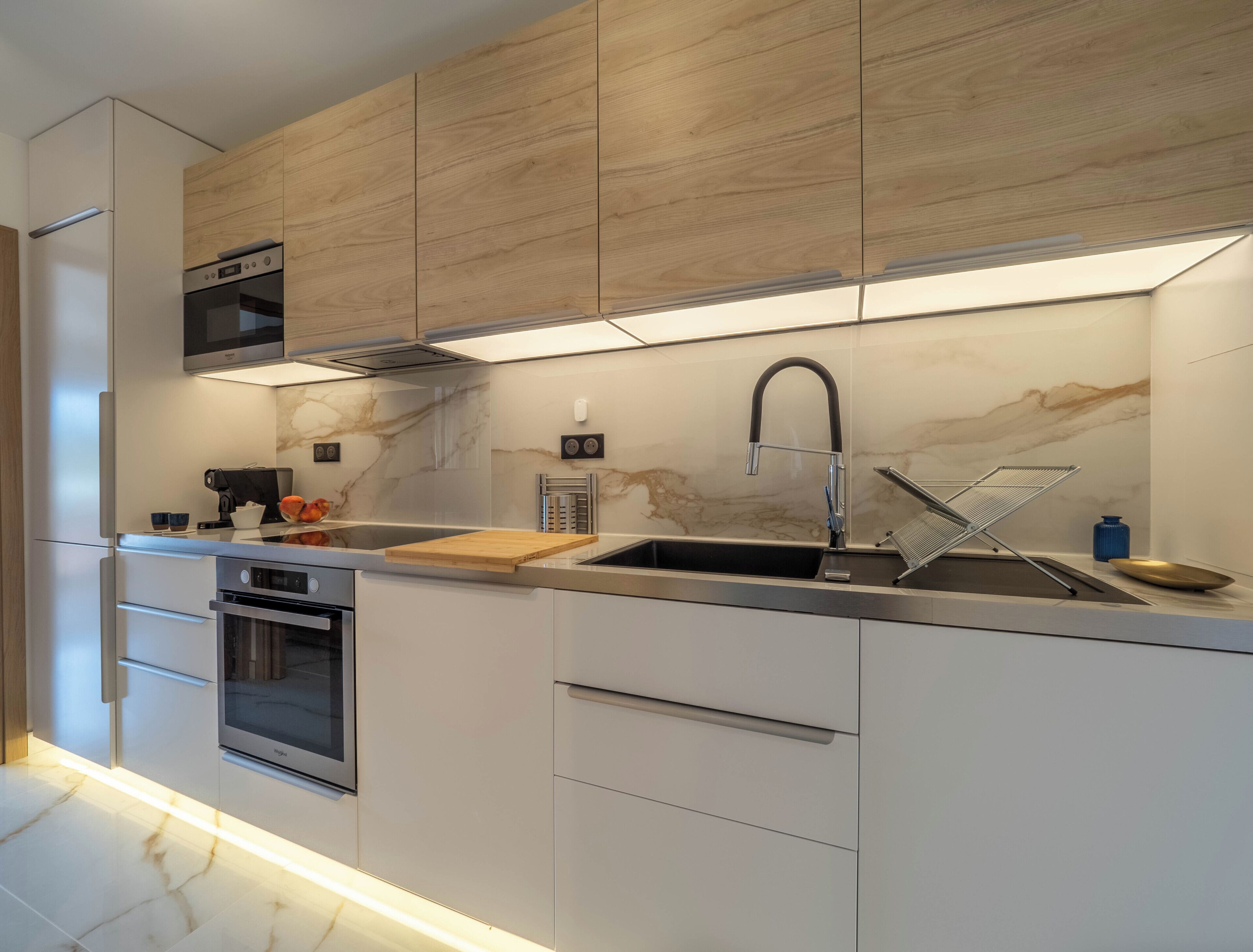 Una cocina moderna con electrodomésticos integrados, un lavaplatos de acero inoxidable y armarios de madera.