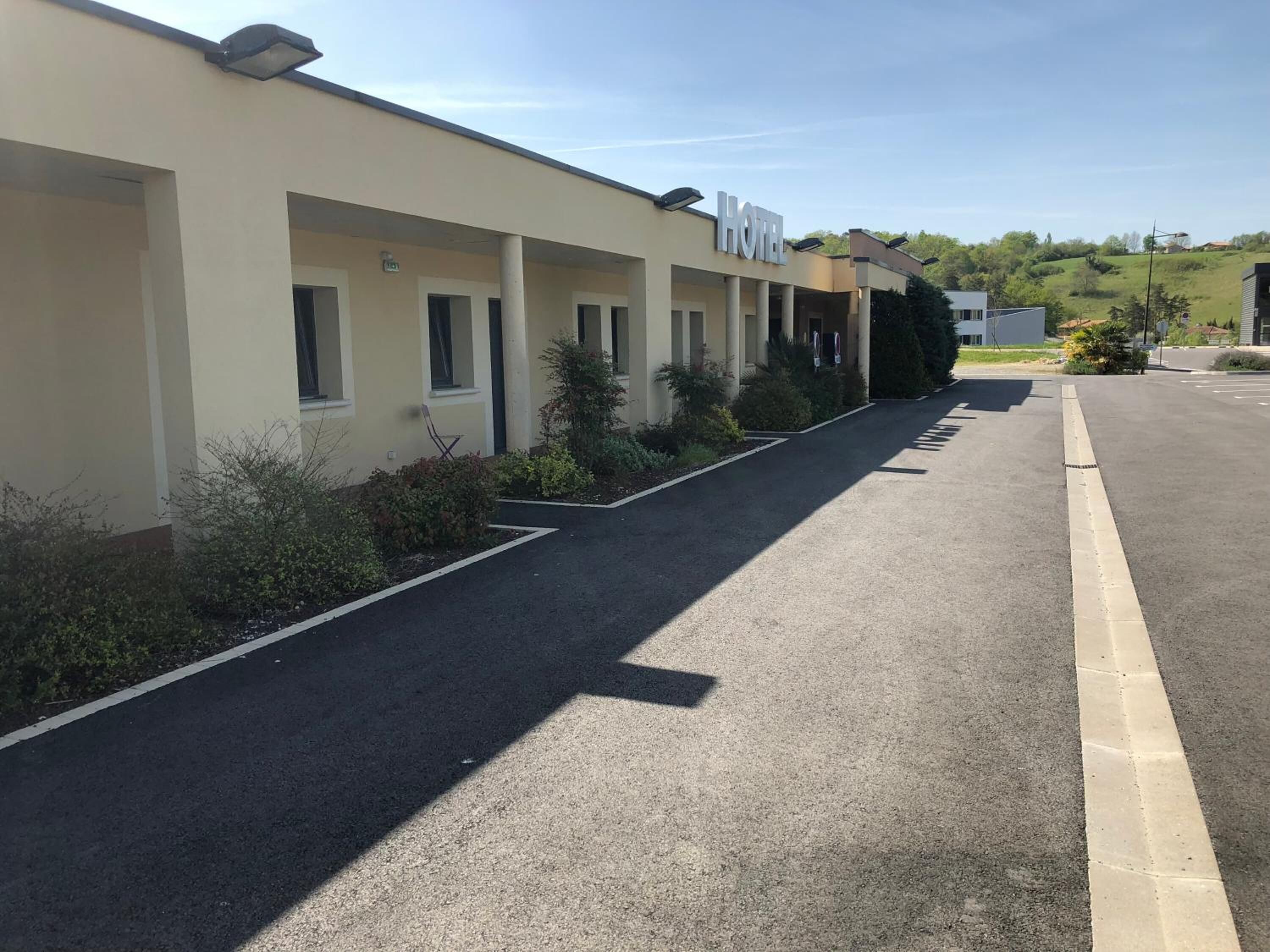 Un hotel con varias habitaciones, un paseo techado y un estacionamiento.