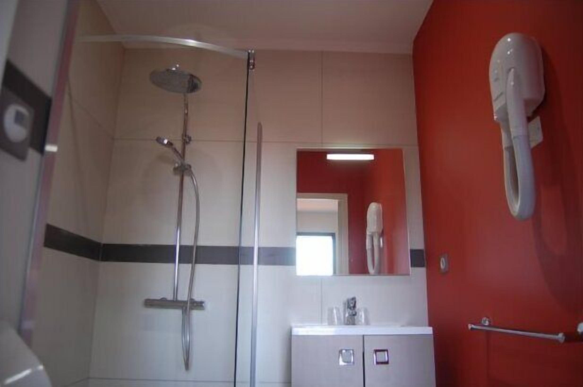 A bathroom with a shower, a sink, and a mirror.