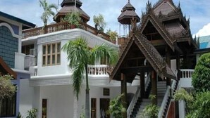 A traditional building with multiple pagoda-style roofs, a white facade, and a staircase leading to a covered area. - Emerald Land Hotel (Mandalay)