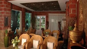 A lobby with wicker furniture, a large vase with flowers, and a decorative golden urn. - Emerald Land Hotel (Mandalay)