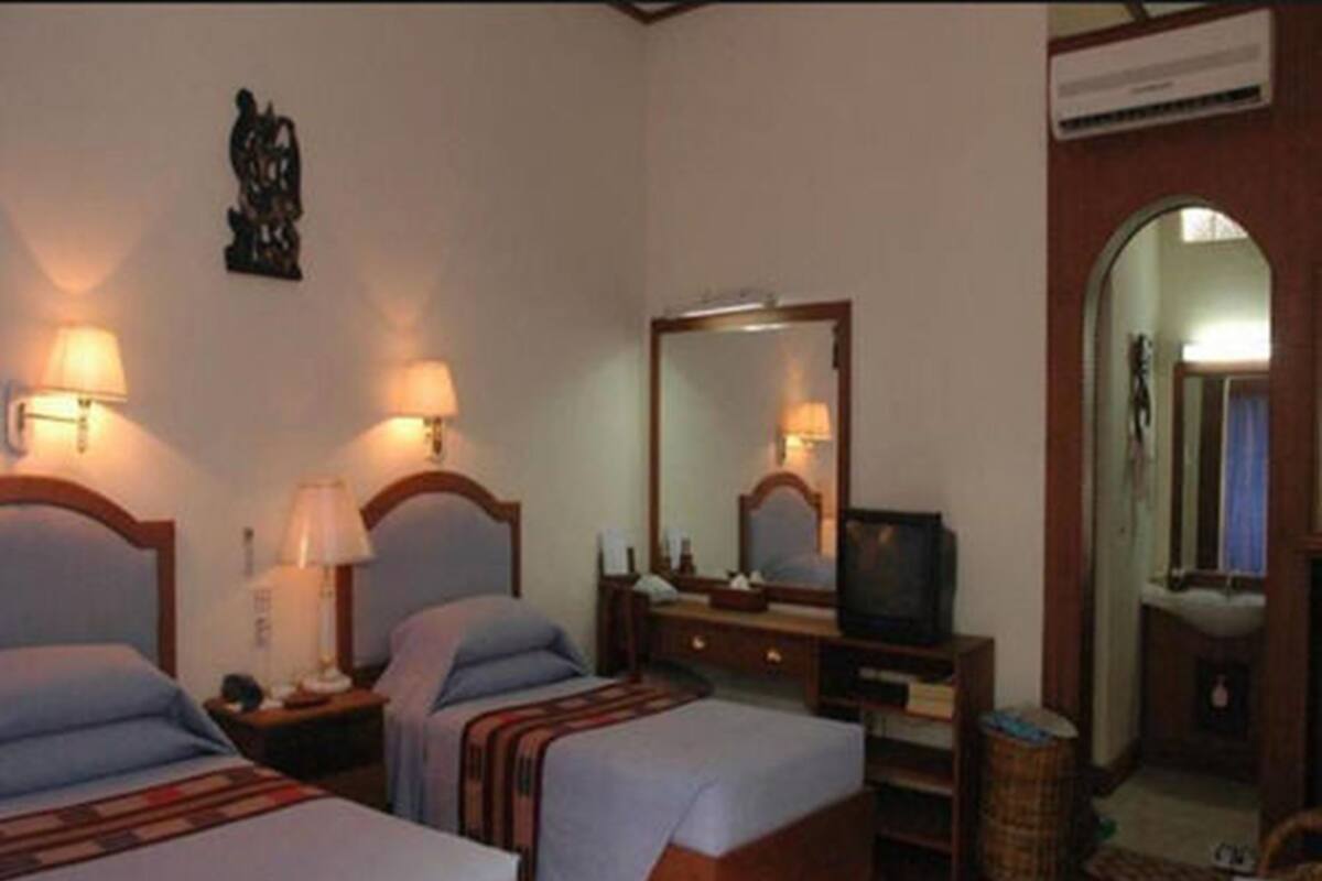 Une chambre d’hôtel avec deux lits, une commode, un téléviseur et un miroir.