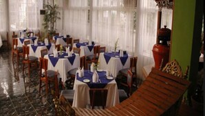 A restaurant with multiple tables, chairs, and a wooden bench. - Emerald Land Hotel (Mandalay)