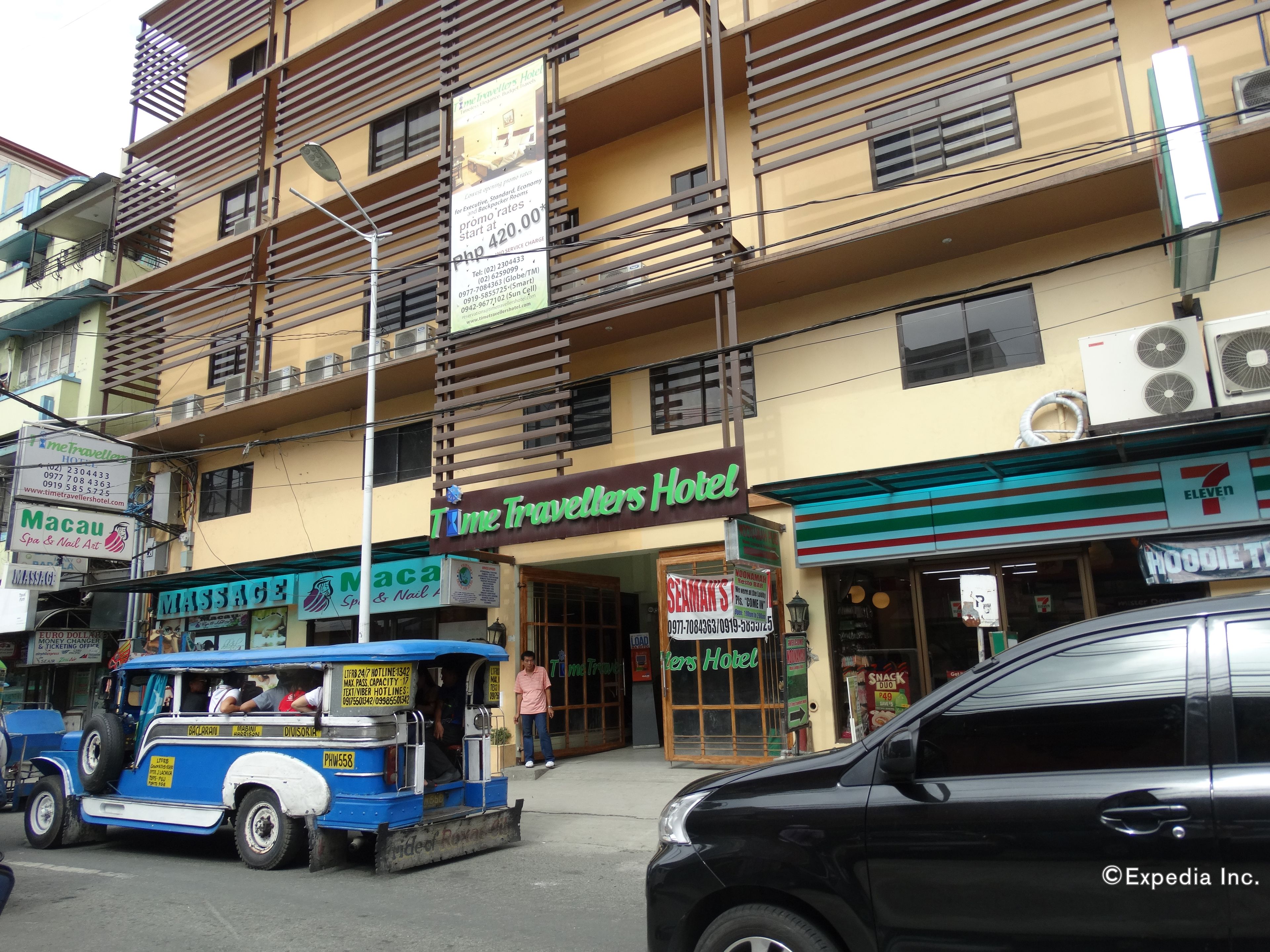 Ein mehrstöckiges Gebäude mit einem Schild für das 'Time Travellers Hotel' und einem 7-Eleven-Geschäft.
