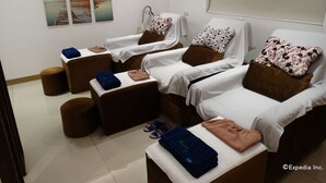 Una habitación con tres camillas para masajes, cada una con una almohada y una toalla. Hay un taburete pequeño y un par de pantuflas en el suelo.
