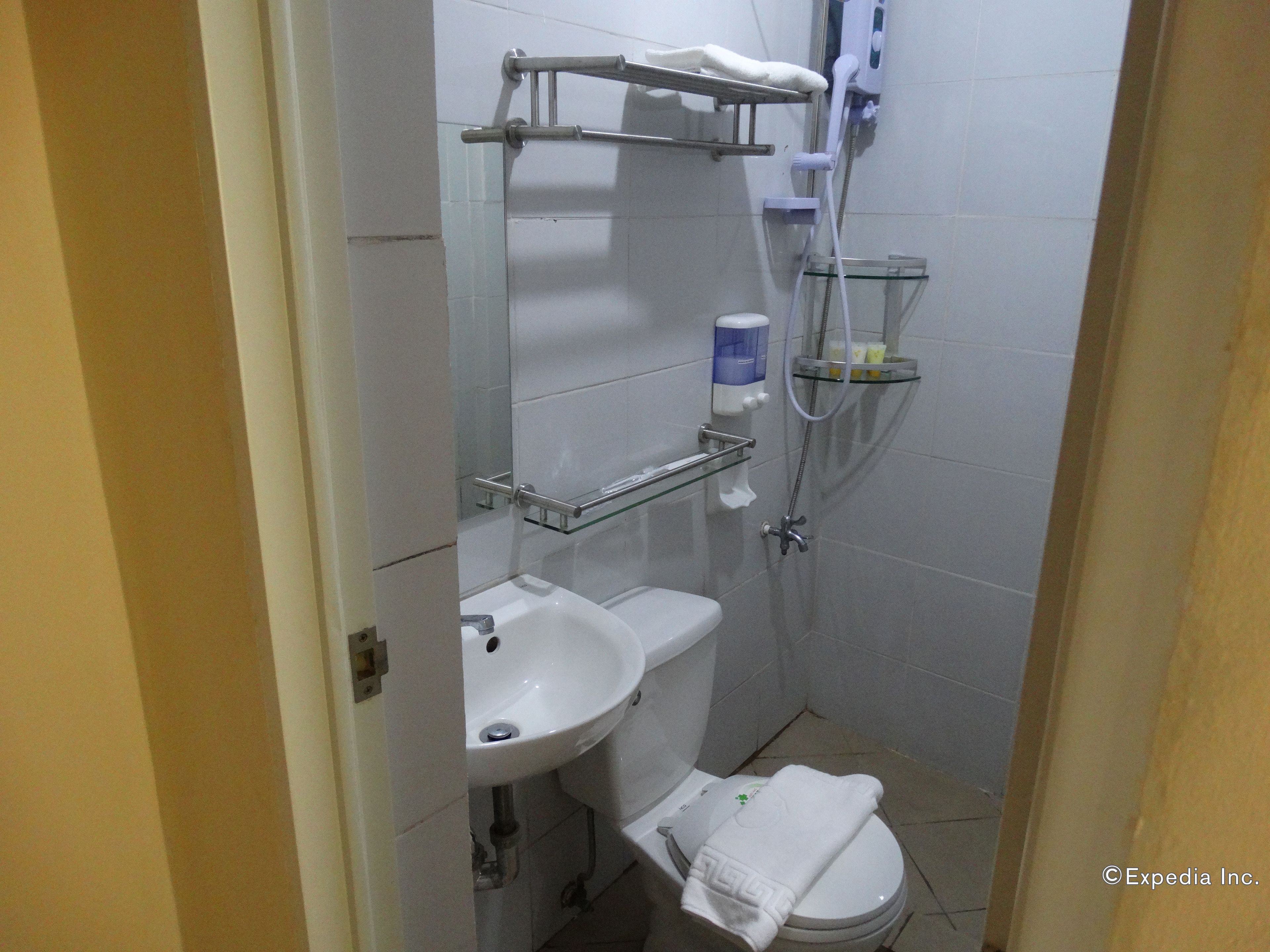 A compact bathroom with a toilet, sink, and shower.