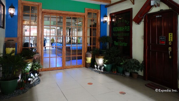 Un pub con fachada verde y azul, puertas de madera y plantas en macetas.