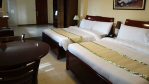 Habitación de hotel con dos camas, un escritorio, una silla y un cuadro en la pared.