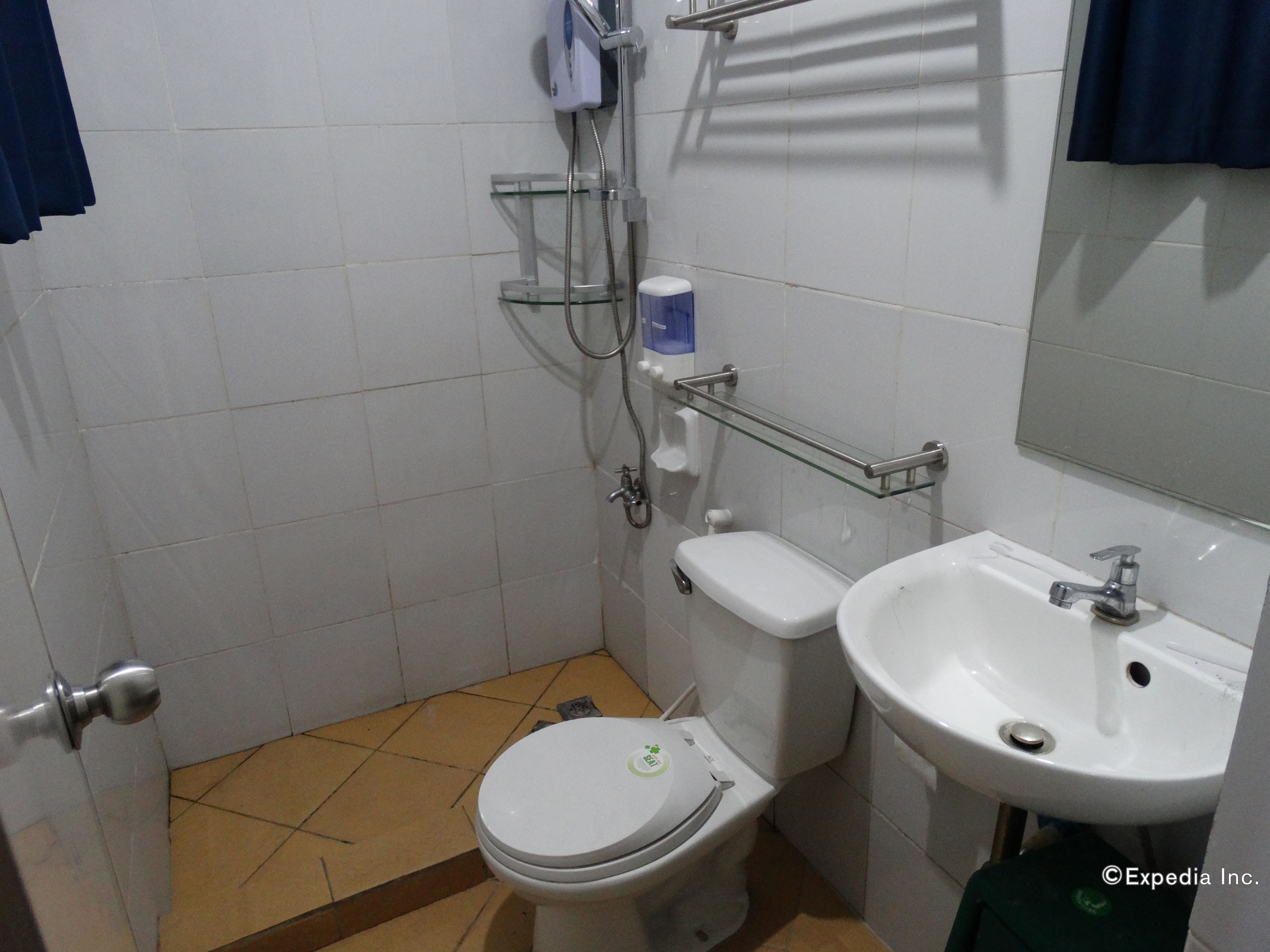 Casa de banho pequena com sanita, lavatório e chuveiro.