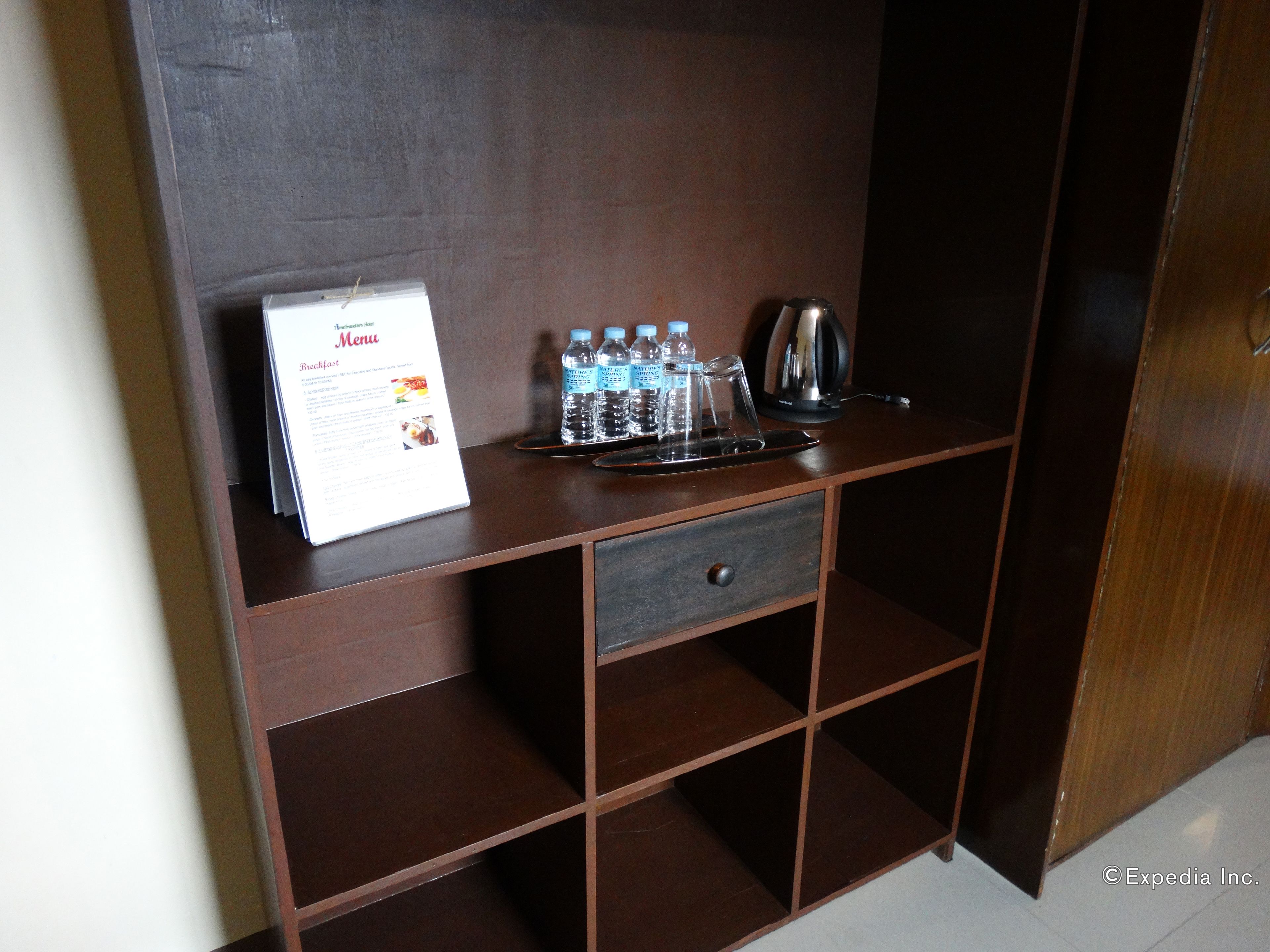 A wooden desk with a menu, water bottles, a kettle, and a coffee pot.