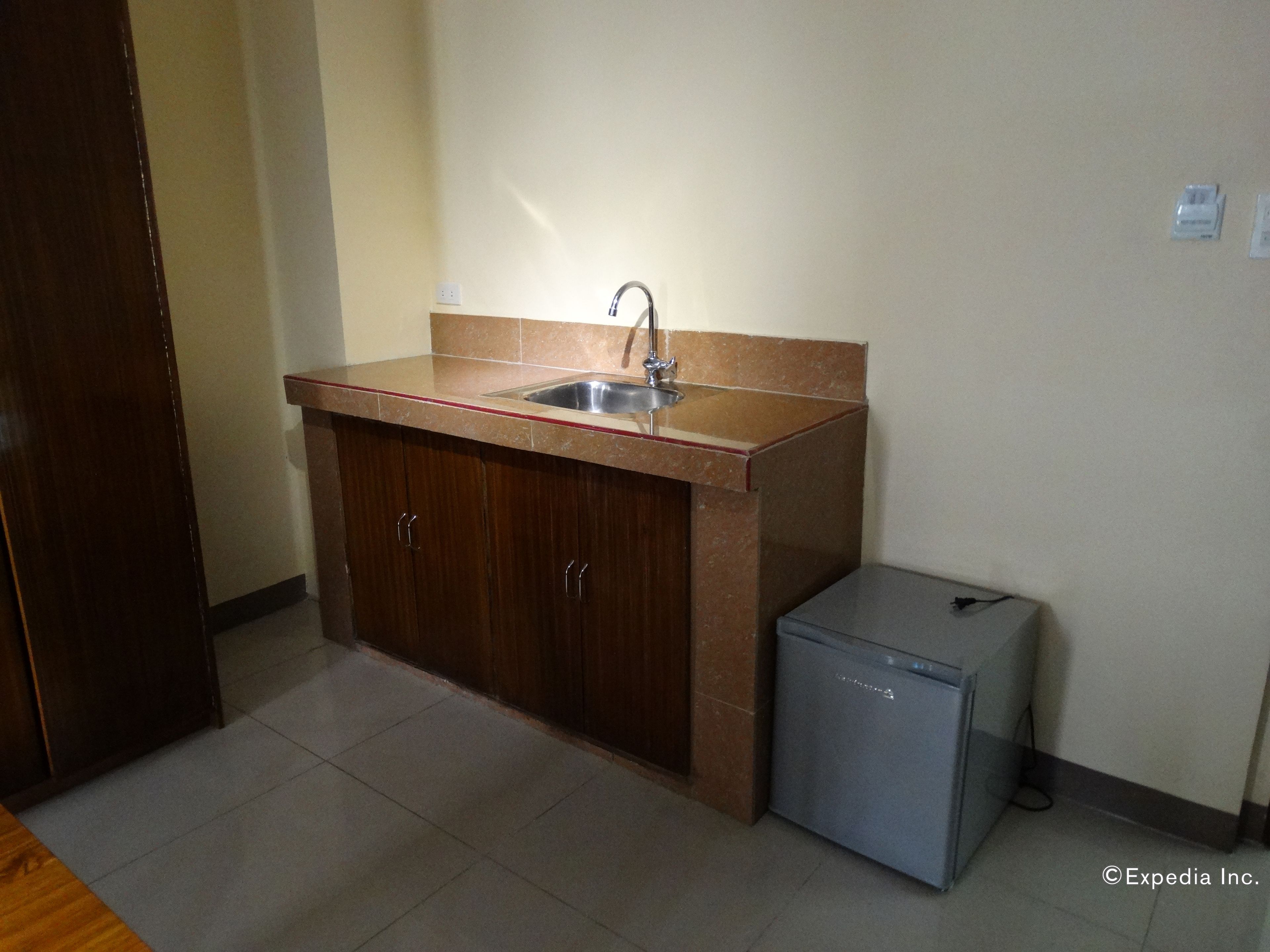 A small kitchen with a sink, cabinets, and a mini fridge.