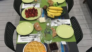 A dining table set with plates, cutlery, a pie, fruits, and beverages. - Top Floor (Naples)