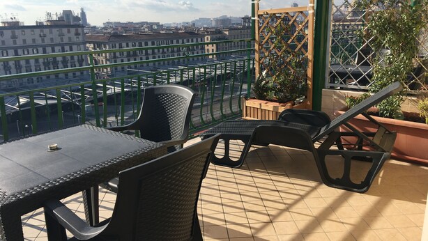 A terrace with a table and chairs, a wooden lattice structure, and potted plants. - Top Floor (Naples)