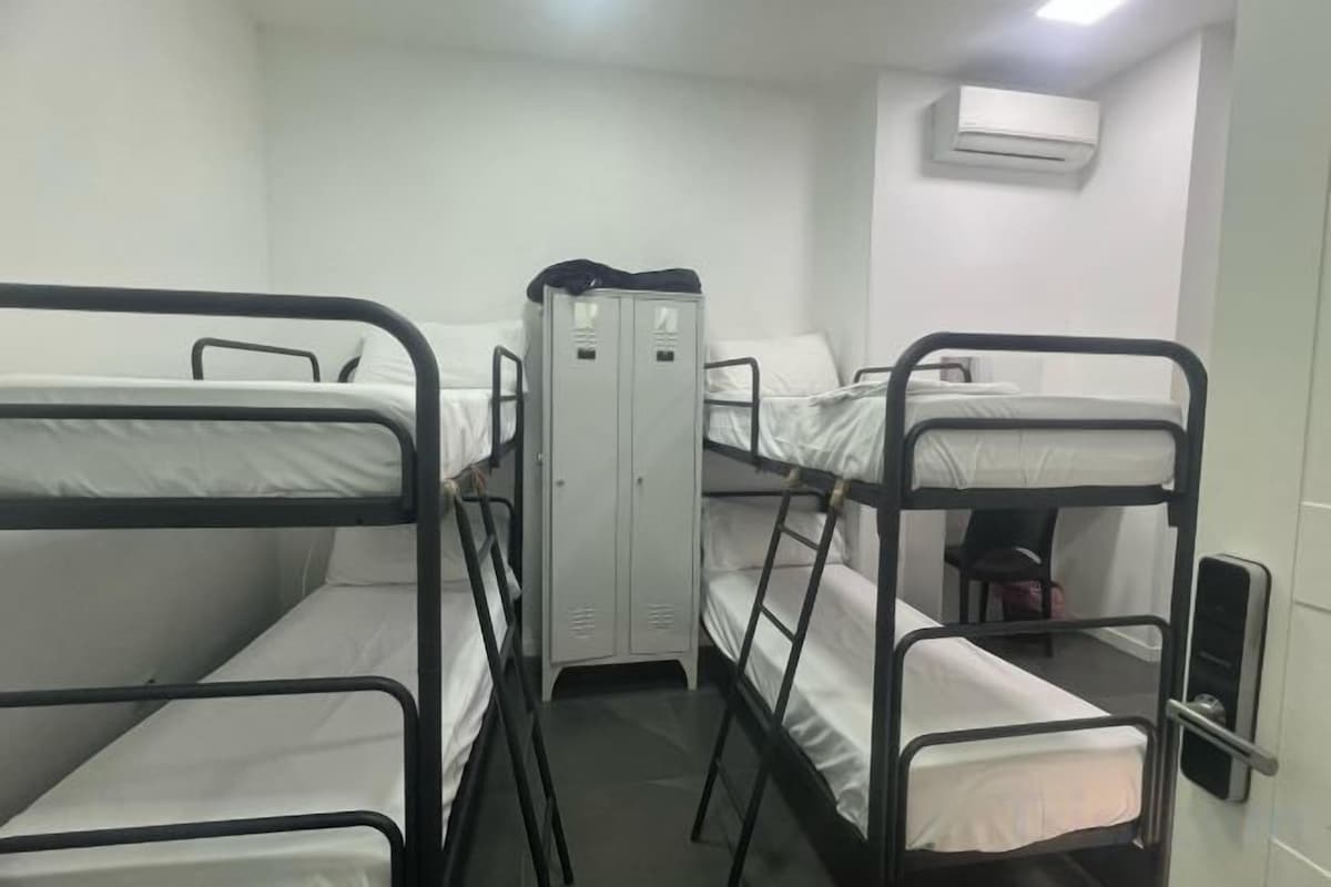 Ein Schlafsaalzimmer mit Etagenbetten, einem Kleiderschrank und einer Klimaanlage.