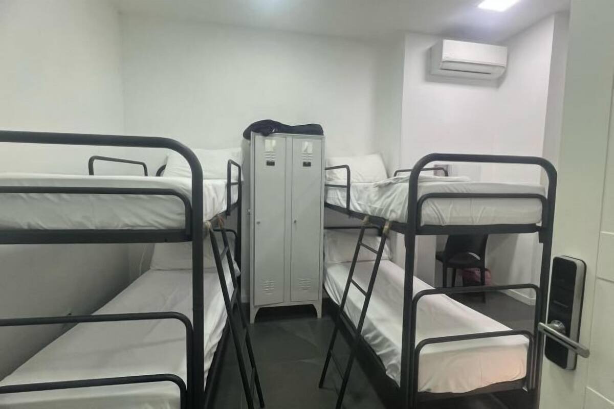 A bunk room with four bunk beds, a wardrobe, and an air conditioning unit.