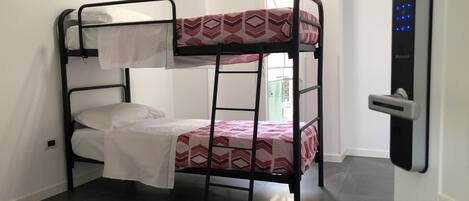 Una cama litera con un edredón estampado, una almohada blanca y estructura de metal negro.