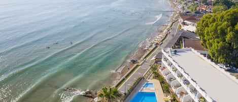 A coastal hotel with a pool, beach access, and a view of the sea.